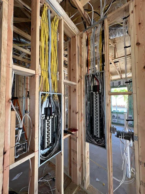 Electrical panels with yellow and black Romex cables, organized wire routing in framed wall cavity