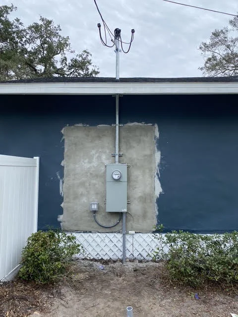 New electrical meter base and service entrance with overhead lines and disconnect switch on concrete pad