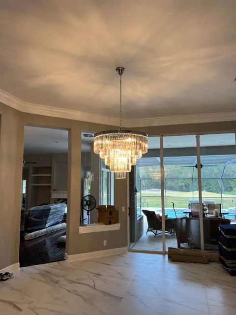 Multi-tier crystal chandelier with chrome hardware suspended in modern living room with marble floors