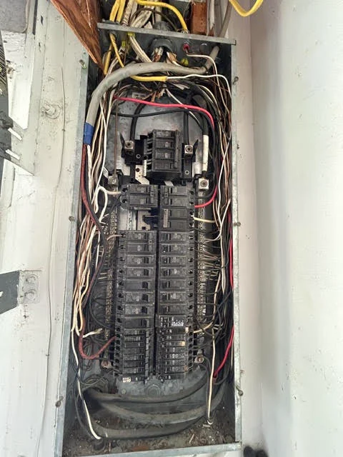 Electrical panel with breaker box, organized wiring, and circuit connections installed in wall enclosure