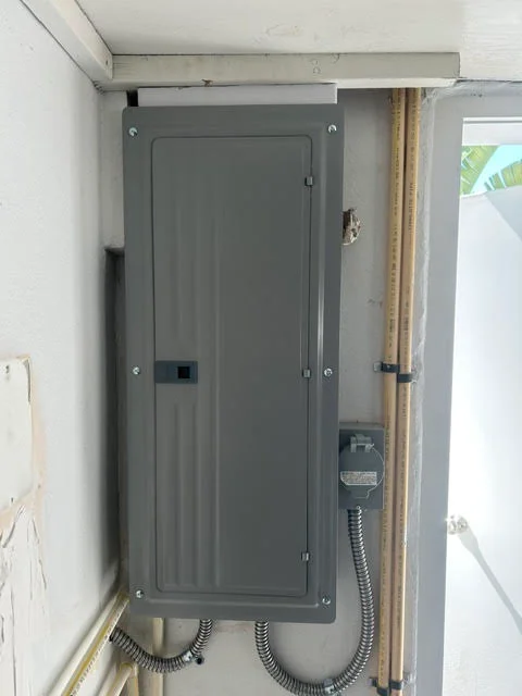 Gray electrical service panel with breaker box and flexible conduit wiring installation