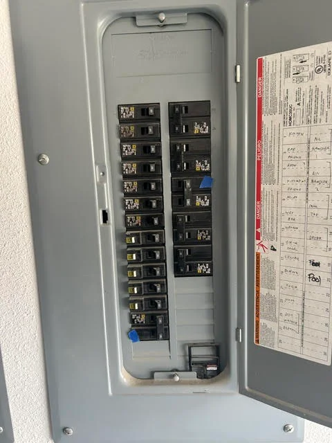 Electrical panel with organized circuit breakers, dual and single-pole configuration, labeled breaker box interior