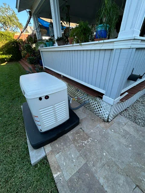 White portable generator on concrete pad with black base platform near residential home