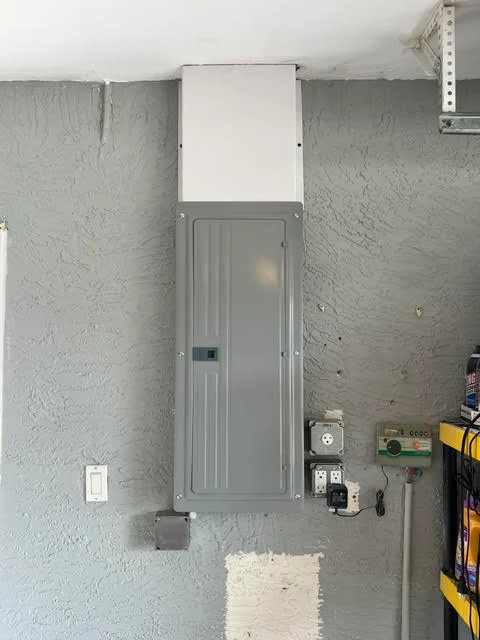 Electrical panel with breaker box mounted on concrete wall with conduit and outlet wiring